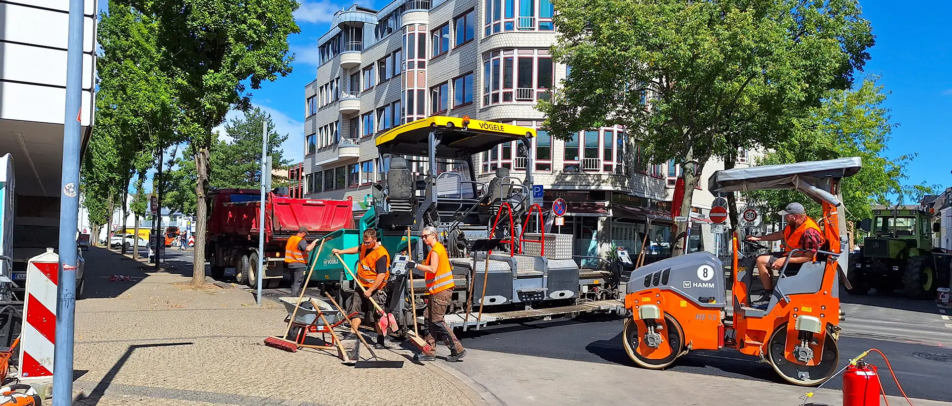 Straßenbau mit Teermaschine und Mitarbeitern